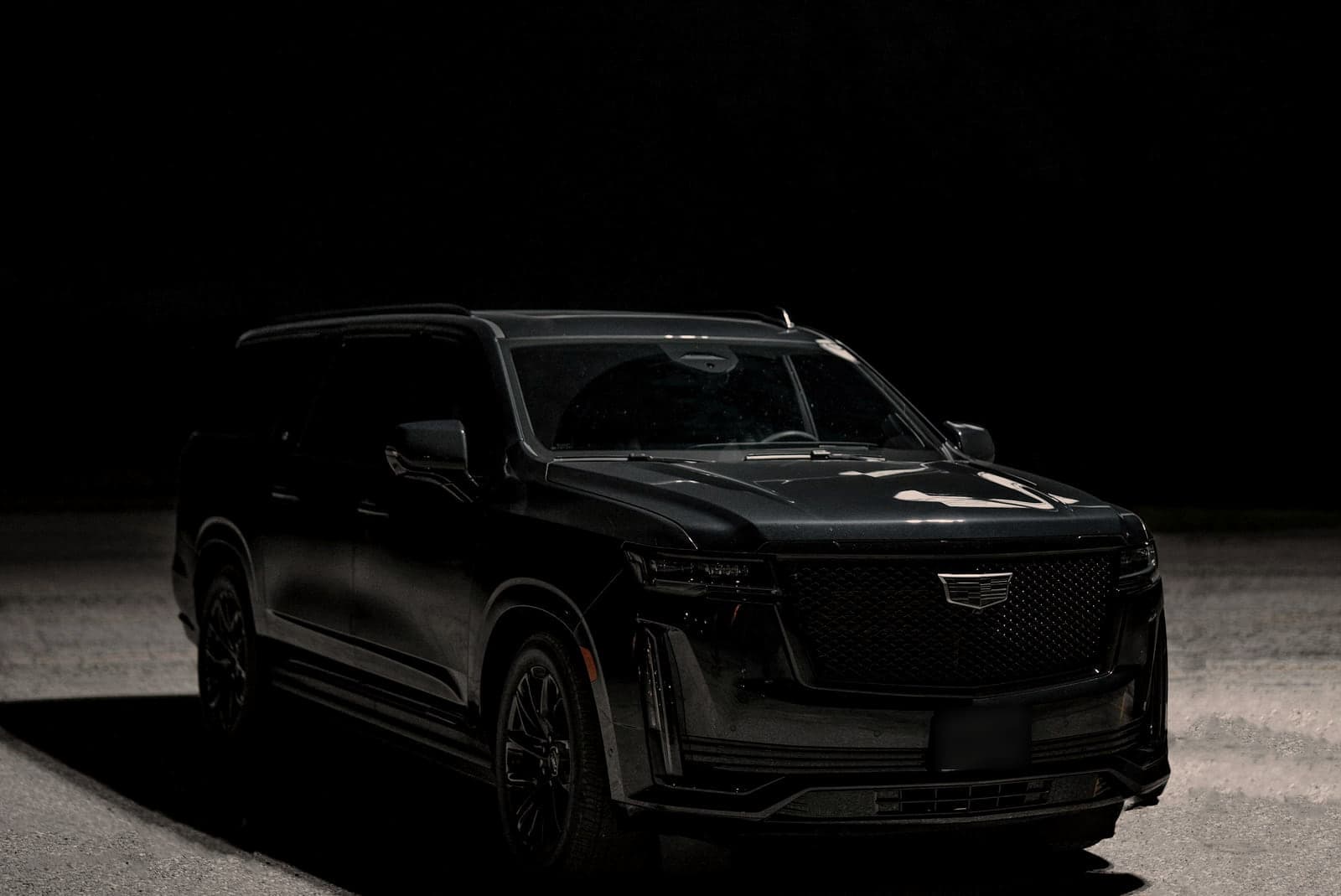 Black full-size SUV parked at night, lit from one side, front three-quarter view